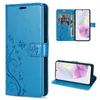Collage of a blue flip phone case with floral and butterfly embossing, showing the case closed, open with cards inserted, and propped up as a stand. Produktbild-Vorschau