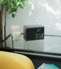 A black PURE Classic H4i DAB+ Internetradio sits on a glass table next to two candles and a plant. Voir les images du produit
