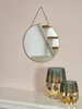 A round mirror hangs on a pink wall above two decorative vases on a white shelf. Produktbild-Vorschau