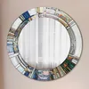 A round mirror with a decorative, abstract stained-glass-like frame. Produktbild-Vorschau