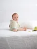 A baby sitting on a bed. Produktbild-Vorschau