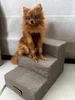 A small brown dog sits on a set of gray pet stairs. Náhled obrázku produktu