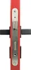 A close-up, straight-on view of a red door lock mechanism with silver metal plates and black protruding parts. Produktbild-Vorschau