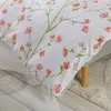 A close-up view of a white bedding set with a delicate floral pattern of pink flowers and green stems. Produktbild-Vorschau