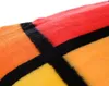 A close-up view of a folded blanket with a geometric pattern of red, orange, and yellow squares separated by black lines. Produktbild-Vorschau