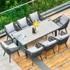 An outdoor patio set with a table and chairs, set on a wooden deck with greenery in the background. Náhľad obrázku produktu