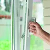 A hand is shown opening a white window with a silver mechanism. Produktbild-Vorschau