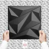 Hands holding a black 3D wall panel against a white geometric background. Produktbild-Vorschau