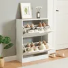 A white shoe cabinet with two flip-down doors, filled with various shoes, is shown in a room with a grey wall and a wooden floor. Podgląd zdjęcia produktu