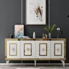A white and gold sideboard with decorative items on top, set against a dark gray wall. Produktbild-Vorschau