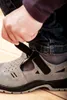 A close-up shot of a person fastening a safety sandal. Produktbild-Vorschau
