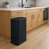 A black trash can is placed in a modern kitchen next to wooden cabinets and a sink. Produktbild-Vorschau