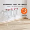A clear acrylic C-shaped table with several bottles of water on top, demonstrating its weight capacity. The background is a plain wall and floor. Náhľad obrázku produktu