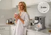 A woman enjoys a cup of coffee in a modern kitchen while an espresso machine brews coffee. Anteprima dell’immagine prodotto