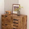 A close-up view of a wooden dresser with drawers and shelves, decorated with a framed picture and a vase of flowers. Podgląd zdjęcia produktu
