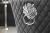 A close-up of a gray upholstered chair with a lion head knocker and ring. Produktbild-Vorschau