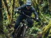 A man riding an e-bike through a lush, green forest. Produktbild-Vorschau