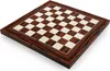 A close-up, angled view of a wooden chessboard with alternating dark and light squares, set against a white background. Podgląd zdjęcia produktu