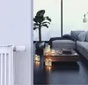 A smart radiator thermostat is attached to a white radiator in a modern living room setting. Náhľad obrázku produktu