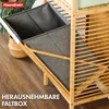 A close-up view of a bamboo shelf unit with a gray fabric storage box partially inserted. The shelf has horizontal slats, and the box is open, revealing its interior. A woven basket is visible behind the box. Náhled obrázku produktu
