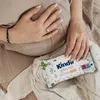 A person's hands are resting on their pregnant belly, holding a pack of baby wipes. Podgląd zdjęcia produktu