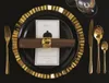 A formal table setting with gold and black cutlery, plates, and a menu. Anteprima dell’immagine prodotto