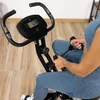 A person using a stationary exercise bike in a home gym setting. Náhľad obrázku produktu