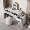 A white vanity table with a cloud-shaped mirror and LED lighting, along with a white stool, is set up in a room with curtains and a plant. Podgląd zdjęcia produktu