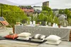 A rooftop terrace set up for a party with a table, cushions, and string lights. Náhled obrázku produktu