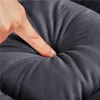 A finger is pressing into a soft, gray cushion, showing its plushness. Podgląd zdjęcia produktu
