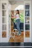 A woman is cleaning a glass door while standing on a step stool inside a home. Produktbild-Vorschau