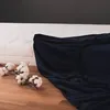 A dark blue fitted sheet is partially covering a white mattress, with cotton branches on the wooden floor. Anteprima dell’immagine prodotto