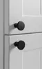 A close-up view of two black cabinet knobs on white cabinet doors. Podgląd zdjęcia produktu