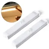 Two white LED light bars with motion sensors are shown on a white background. A circular inset shows a hand touching a similar light bar mounted under a shelf, illuminating it. Produktbild-Vorschau