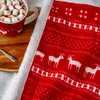 A close-up view of a red and white patterned blanket with a mug of hot chocolate and marshmallows on a wooden tray. Podgląd zdjęcia produktu