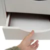 A hand is shown pulling open a white drawer of a piece of furniture, possibly a nightstand or bookshelf. Voir les images du produit