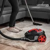 A person is vacuuming a rug in a living room with a LEHMANN vacuum cleaner. Produktbild-Vorschau