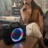 A woman is singing into a microphone next to a portable speaker with colorful lights. Produktbild-Vorschau