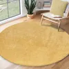 A round yellow rug in a living room setting with a chair and a plant. Produktbild-Vorschau