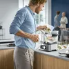 A man is using a sous vide cooker in a kitchen, with other people in the background. Produktbild-Vorschau