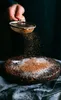 A person is dusting a cake with cocoa powder. Produktbild-Vorschau