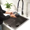 A person is rinsing a dustbin in a kitchen sink. Voir les images du produit