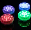 Four round LED lights in red, blue, green, and purple are displayed on a reflective black surface. Produktbild-Vorschau