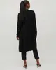 A woman wearing a black cardigan and pants, viewed from the back. Produktbild-Vorschau