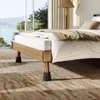 A bed with risers, set in a well-lit room with a view of nature. Produktbild-Vorschau