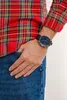 A person wearing a red plaid shirt and blue jeans, with a blue watch on their wrist. Podgląd zdjęcia produktu