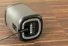 The back of a portable speaker is shown plugged into a charging cable, resting on a wooden surface. Anteprima dell’immagine prodotto