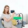 A woman is sitting on a couch, holding a smartphone attached to a flexible arm holder. Podgląd zdjęcia produktu