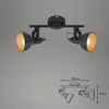 A black and gold metal spotlight with two adjustable heads, shown against a plain gray background. A technical drawing with dimensions is also included below the product. Produktbild-Vorschau