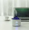 A white aroma diffuser shaped like a volcano is placed on a white desk next to a laptop and a cup of coffee. Náhľad obrázku produktu